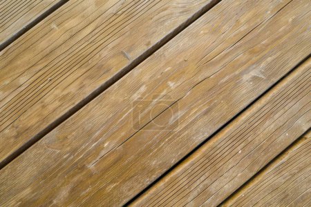 This image displays weathered wooden deck planks bathed in sunlight, highlighting their rich textures and visible grain patterns.