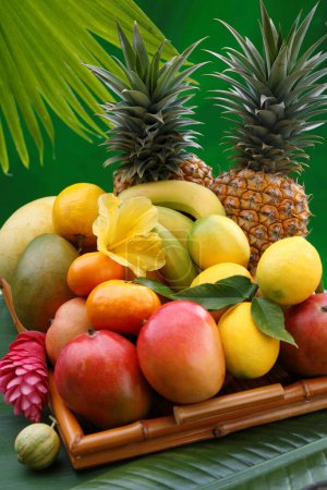 Foto de Cesta de frutas tropicales exóticas con flores tropicales en una hoja de palma - Imagen libre de derechos
