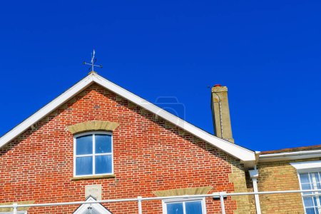 Téléchargez les photos : Fermez la récolte d'une maison anglaise en briques rouges contre un ciel bleu sans nuages - en image libre de droit