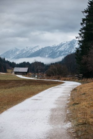 Téléchargez les photos : Vue d'une route sinueuse menant à une maison en bois solitaire dans les montagnes - en image libre de droit