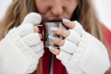 Téléchargez les photos : Young woman drinks a cup of hot tea or coffe in winter outdoors - en image libre de droit