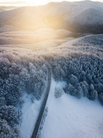 Foto de Aerial view of winding road from high mountain pass with snow-covered trees in Transylvania, Romania. Nature travel concept. - Imagen libre de derechos
