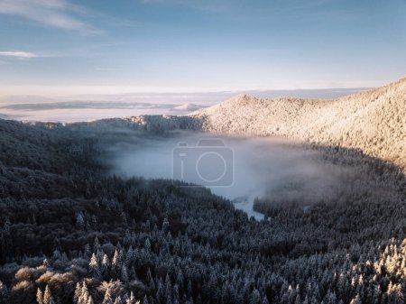 Téléchargez les photos : Morning clouds over snowy mountain lake during winter at sunrise. Saint Anne Lake is the only one crater volcanic lake from Romania. - en image libre de droit