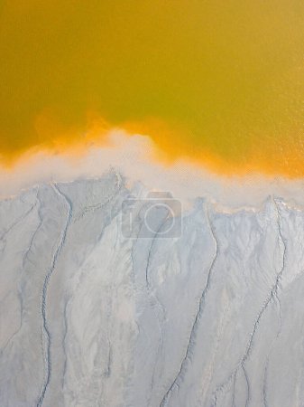 Aerial view of contaminated, toxic water stream in Geamana, Rosia Montana, Romania. Yellow, orange, white abstract background.