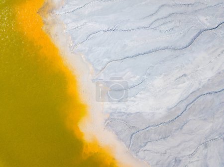 Aerial view of an abandoned Romanian village drowned beneath toxic lake of fluorescent yellow sludge in Geamana,Rosia Montana,Transylvania. Yellow, orange, white abstract background.