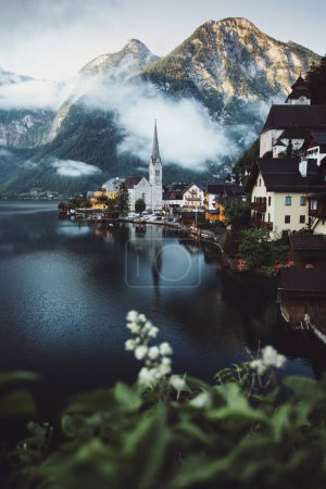 Téléchargez les photos : Moody view of famous beautiful old town Hallstatt and alpine deep lake in scenic foggy morning. Summer season, creative, vintage style - en image libre de droit