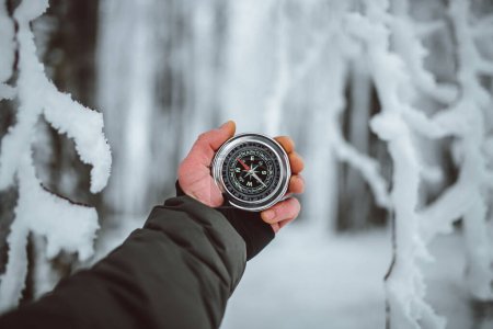 Téléchargez les photos : Man holding compass in hand on the background of the winter forest - en image libre de droit