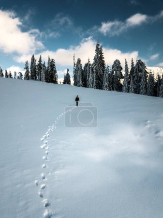 Young traveler girl walking in the deep snow, captured from above with drone