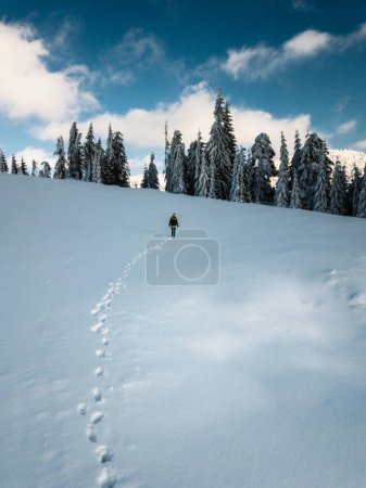 Young traveler girl walking in the deep snow, captured from above with drone