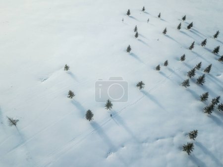 Foto de Aerial view of man walking with snow in winter time - Imagen libre de derechos