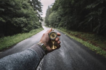 Photo for Male hand with compass on background of road in the forest, point of view. - Royalty Free Image