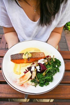 Photo for Woman hold the healthy crispy salmon with kale. Healthy eating lifestyle habit. Self love, self care for physical, mindfulness eating. Concept. Healthy nutrition, diet good nutrition. - Royalty Free Image