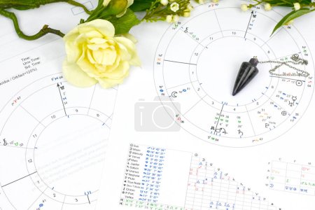 Téléchargez les photos : Printed astrology birth chart and white flowers and pendulum , workplace of astrology, spiritual, The callings, hobbies and passion, blueprints and life mapping - en image libre de droit