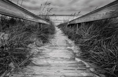 A boardwalk leads to the ocean at Jacksonville Beach, Florida at high tide under stormy skies.