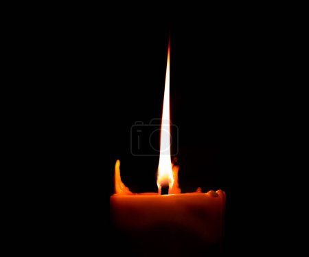 Burning big candle on dark candle holder and black background, space for text on top. Buddhism Memory day