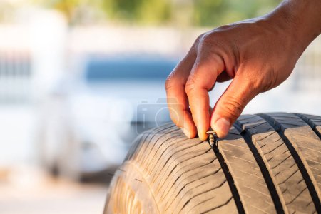 Photo for The mechanic was using his hands to remove a nut ro nail from a tire that had been stepped on and caused a puncture. Accidents while driving on the road concept - Royalty Free Image