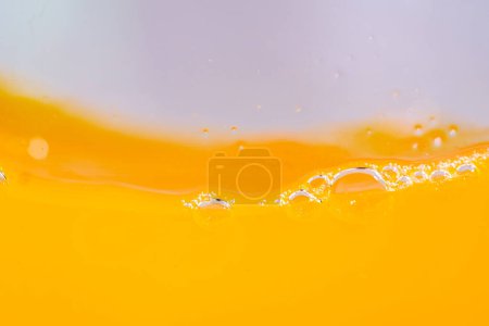 Primer plano brillante jugo de naranja salpicadura textura para la salud y las olas de la naturaleza, hermosas olas curva y pequeñas burbujas suave para el diseño y el fondo trófico