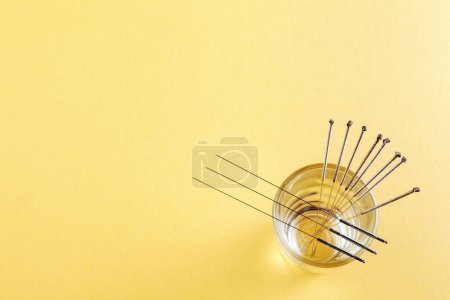 Silver needles for traditional Chinese medicine acupuncture. Yellow background. Close-up. There is some free space for your text or sign.