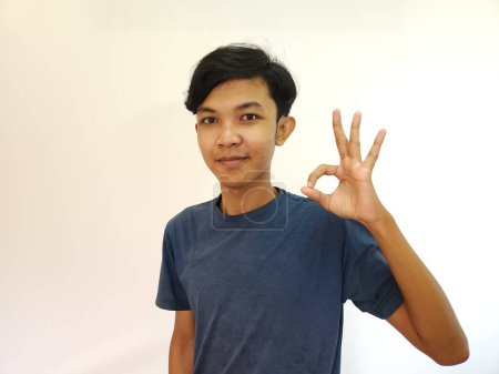 Téléchargez les photos : Heureux asiatique l'homme montre OK main geste comme un bon main signe isolé sur blanc fond - en image libre de droit