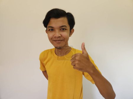 Foto de Feliz asiático hombre muestra pulgar arriba como un bueno mano signo aislado en blanco fondo - Imagen libre de derechos