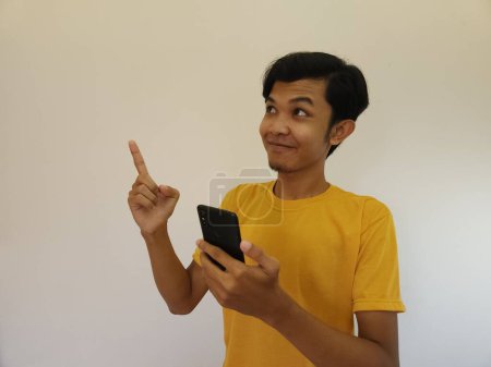 Foto de Hombre asiático señalando el espacio de copia. un hombre sosteniendo un teléfono inteligente, fondo blanco aislado - Imagen libre de derechos