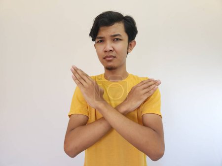 Téléchargez les photos : Portrait de jeune homme asiatique beau montrant l'expression STOP ou Rejet croisant les bras faisant signe négatif, visage en colère, fond isolé de couleur bleue - en image libre de droit