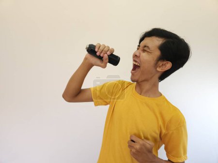 Photo for Portrait of young handsome Asian man singing a song with a microphone. happy and relax, enjoy the moment - Royalty Free Image
