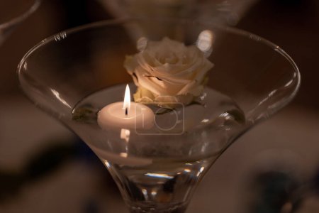 Téléchargez les photos : Martini verre avec de l'eau, rose et bougie mariage mis en place - en image libre de droit