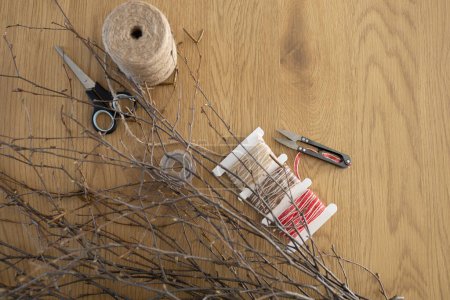 Zubehör für die Herstellung von DIY Weidenkranz aus Birkenzweigen auf Holztischhintergrund. Kranzflechten, handgemachte Dekoration