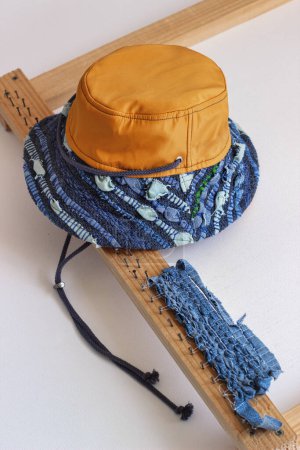 Foto de Sombrero de Panamá fabricado en tejido reciclado. Reciclaje de textiles. Tejido de vaqueros viejos. Reciclar cosas viejas y hacer otras nuevas. Subiendo en bicicleta. Moda sostenible. Reciclar textiles - Imagen libre de derechos