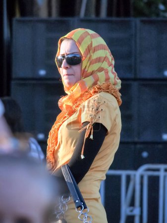 Photo for Kharkiv,Ukraine - July 01,2012: Stylish islamic woman wearing in orange yellow hijab of the colors of football team of netherlands and sunglasses on the eve of final of Euro 2012. Refined beauty in the east in a European metropolis. - Royalty Free Image