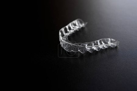 Photo for Transparent invisible orthodontic brackets, tooth aligners, plastic braces, mouth guard, retainers on a black background - Royalty Free Image