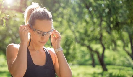 Photo for Close up Sport woman sportswear and headphones tie laces while training jogging running outside in green park banner, copy space for design. - Royalty Free Image