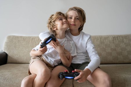 Téléchargez les photos : Enfants mignons joyeux jouant à des jeux vidéo avec console de commande, frère soeur exprimant des émotions tout en appréciant leur joystick hobby playstation - en image libre de droit