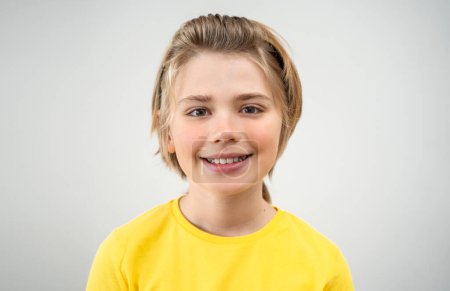 Photo for Close-up Pre-Adolescent Boy Child In Yellow T-Shirt with Long Hair Smiling Looking At Camera Over White Background. Copy Space For Design Advertisement - Royalty Free Image