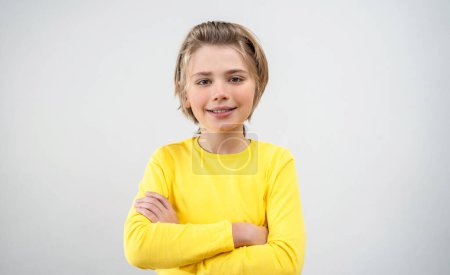 Photo for Pre-Adolescent Boy Child In Yellow T-Shirt with Long Hair Smiling Looking At Camera Over White Background. Copy Space For Design Advertisement - Royalty Free Image