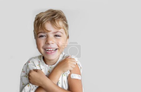 Foto de Niño después de la vacunación con una venda adhesiva en el brazo del parche para prevenir cualquier infección sobre el fondo blanco. Concepto positivo de estilo de vida saludable y cuidado. - Imagen libre de derechos