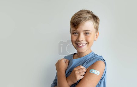 Photo for Child after vaccination with a adhesive band-aid patch arm bandage to prevent any infection over white background. Positive concept of healthy lifestyle and care. - Royalty Free Image