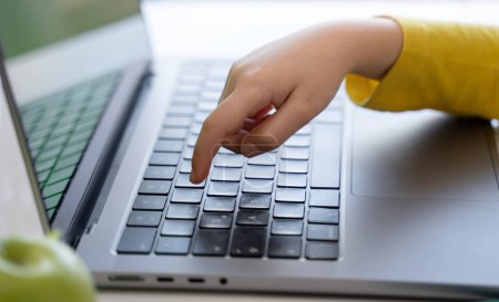 Photo for Close-up of child hands typing on the keyboard laptop. Distance learning online education. Schoolboy girl studying at home with digital tablet notebook and doing school homework. - Royalty Free Image