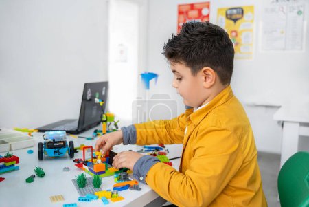 Photo for Robotics lego programming class. Children construct and code Robot Lego. STEM education using constructor blocks and laptop, remote control joystick. Technology educational development for school kids - Royalty Free Image