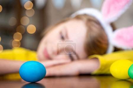 Téléchargez les photos : Traditions familiales de Pâques. Gros plan enfant caucasien avec des oreilles de lapin jouant avec des œufs multicolores décorés. Un gamin qui s'amuse. Espace de copie négatif - en image libre de droit