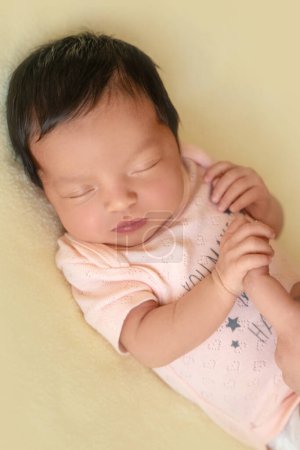 Photo for Newborn baby infant with dark hair lying on side sleeping holding mother finger. Cute little Middle eastern child on blanket. Tranquil scene close up - Royalty Free Image