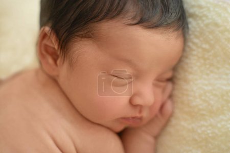 Téléchargez les photos : Bébé nouveau-né aux cheveux foncés couché sur le côté dormant. Mignon petit enfant du Moyen-Orient sur couverture. Espace de copie de scène tranquille pour la publicité - en image libre de droit