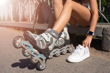 Téléchargez les photos : Gros plan fille portant des patins à roues alignées rouleaux se préparant dans le parc public en été. Adolescent loisirs de plein air jeu d'activité sportive. - en image libre de droit
