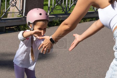 Photo for Mother teaching child daughter to skate on inline skates rollers in public park in summer. Family leisure outdoor sport activity game. Copy negative space - Royalty Free Image