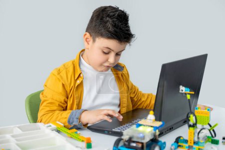 Photo for Robotics programming class. Children construct and code Robot. STEM education using constructor blocks and laptop, remote control joystick. Technology educational development for school kids - Royalty Free Image