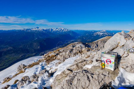 Foto de La cumbre de Stol en las montañas de Karawanke (Eslovenia) con el estuche del libro de bitácora en primer plano. Julián Alpes en el fondo, - Imagen libre de derechos