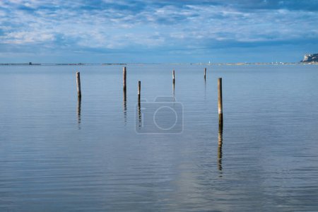 Photo for Six wooden posts protruding from the sea surface on the Slovenian coast near Secovlje - Royalty Free Image