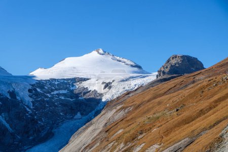Téléchargez les photos : Sommet enneigé de Johannisber avec une pente herbeuse et glacier Pasterze en dessous - en image libre de droit