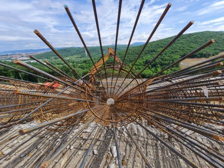 Foto de Jaula de refuerzo de malla de acero para pilotes geotécnicos en una obra de construcción, excavadora en segundo plano - Imagen libre de derechos